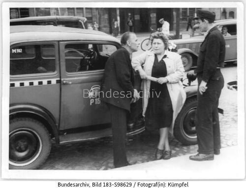 Taxifahrerin an Taxi lehnend