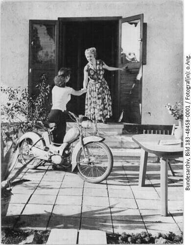 Mädchen mit Motorrad vor Hauseingang